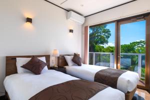 due letti in una stanza con una grande finestra di KOURI Ocean Moon Cottage - Vacation STAY 05891v a Kouri Altre 34 foto