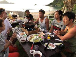 a group of people sitting around a table eating food at Amami Lucky House - Vacation STAY 07619v in Amami