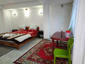 a bedroom with a bed and a table with a green chair at Sat Chit Ananda bhavan in Darjeeling