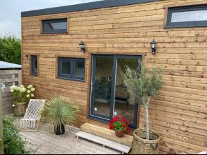 een houten huis met planten ervoor bij La Tiny d'Utah Beach - Proche de la plage in Sainte-Marie-du-Mont
