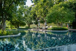 a swimming pool in a park with trees at The Peri Hotel Khao Yai in Phayayen