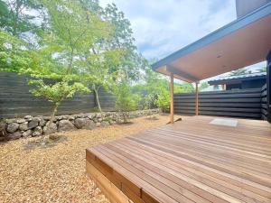 a wooden deck in a backyard with a stone wall at Karuizawa House Villa - Vacation STAY 16955v in Oiwake