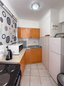 a kitchen with wooden cabinets and a white refrigerator at SolSands Hotel & Self-Catering in Durban +18 photos