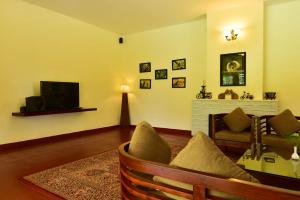 a living room with a couch and a television at Monica Garden Bungalow in Vālpārai