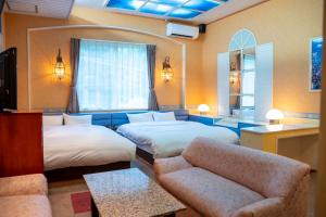 a hotel room with two beds and a couch at Farm Garden Hotel in Numazu