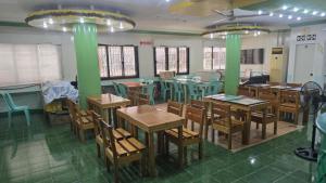 a restaurant with wooden tables and chairs and green columns at Green Mellow Court Osmena in Dipolog