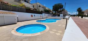 two swimming pools in a courtyard in front of a building at Argaka Breeze sea view apartment in Argaka
