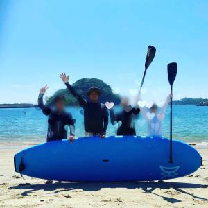 Rural house for rent - Vacation STAY 18282v في Susami: مجموعة من الأشخاص يقفون على الشاطئ مع لوح ركوب الأمواج الأزرق