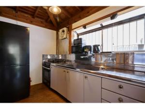 a kitchen with a black refrigerator and a sink at Kayabuki Kominka Syuzenji - Vacation STAY 18448v in Izu