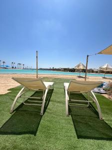 two chairs sitting on the grass near the beach at Le sidi Luxury Hotel Cabana Hacienda bay in El Alamein +7 photos