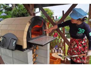 ŌyaにあるDaichan Farm Guest House - Vacation STAY 19124vの女が屋外のオーブンで料理している