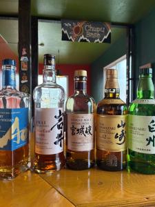 un groupe de bouteilles de whisky posées sur une table dans l'établissement Maeda Forestry House - Vacation STAY 19585v, à Furano