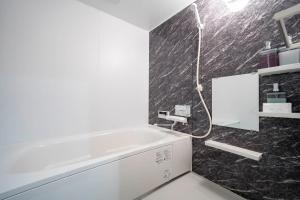 a bathroom with a white tub and black tiles at Mks 202 in Asahikawa