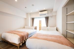 two beds in a room with a window at Tomariehoteru & kondominiamu - Vacation STAY 19483v in Hakata