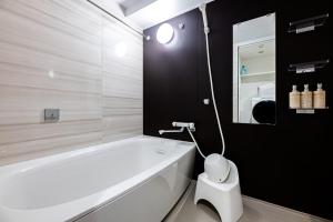 ein Badezimmer mit einer weißen Badewanne und einem WC in der Unterkunft Tomariehoteru & kondominiamu - Vacation STAY 19482v in Hakata + 9 Fotos