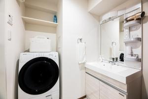 eine Waschküche mit Waschmaschine und Waschbecken in der Unterkunft Tomariehoteru & kondominiamu - Vacation STAY 19482v in Hakata