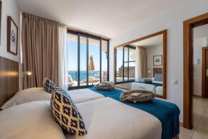 two beds in a room with a view of the ocean at Servatur JB - Adults Only in Puerto Rico de Gran Canaria