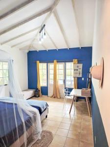 Un dormitorio con paredes azules y una cama y un escritorio. en Villa Solazur, en Bocas Town