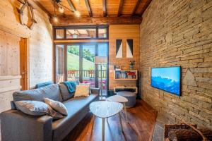 a living room with a couch and a brick wall at L'Escampette à la Fontanette in Saint-Pancrace
