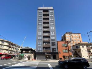 a tall building on a city street with a car at Rakuten STAY Kyoto Station Standard Twin Room in Kyoto