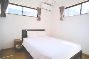 a white bed in a room with two windows at Wataru DUO - OKINAWA - Vacation STAY 26735v in Inbu