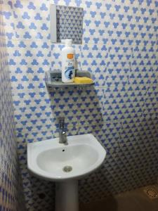 La salle de bains est pourvue d'un lavabo blanc et de carrelage bleu et blanc. dans l'établissement Accueil Kounoune, à Kounoun