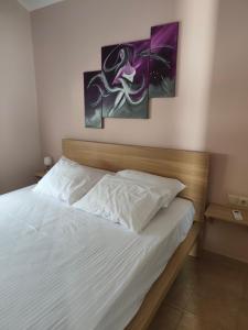 a bedroom with a bed with three paintings on the wall at Rias Efthimiou House in Kanallaki +35 photos