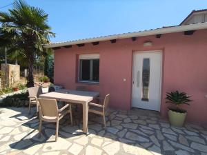 een patio met een tafel en stoelen voor een roze huis bij Rias Efthimiou House in Kanallákion