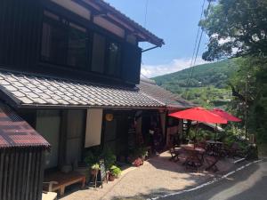 - un bâtiment avec une terrasse dotée d'une table et d'un parasol dans l'établissement Hatago Masara - Vacation STAY 30108v, à Tanabe