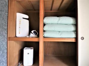 ein Holzregal mit Handtüchern und anderen Gegenständen darauf in der Unterkunft Maison Ota Building A Building B - Vacation STAY 11098 in Takamatsu