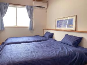2 letti in una camera da letto con lenzuola blu e finestra di KR base Villa IzuShirahama Resort - Vacation STAY 33293v a Shimoda Altre 20 foto