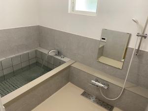 ein Badezimmer mit einer Dusche und einer Badewanne mit einem Spiegel in der Unterkunft KR base Villa IzuShirahama Resort - Vacation STAY 33296v in Shimoda