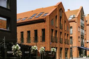 a red brick building with windows on a street at Victory Love Apartaments! in Klaipėda