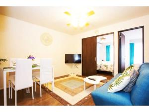 ein Wohnzimmer mit einem blauen Sofa und einem Tisch in der Unterkunft Hill Top Hakone Iryuda 202 - Vacation STAY 11214 in Odawara