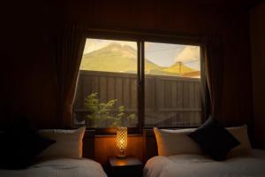a bedroom with two beds and a window with a view at Tabi no yado Hanakeshiki Jinchoge 1st floor - Vacation STAY 42964v in Yufuin