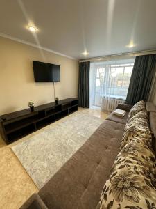 a living room with a couch and a flat screen tv at Абдирова 19 в центре in Karagandy