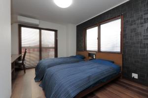 a bedroom with a bed with a blue comforter and two windows at ROYAL SUITE SAKAE - Vacation STAY 11483 in Nagoya