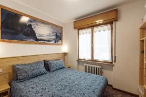a bedroom with a bed and a picture on the wall at Dolomitohouse PEZ in Fiera di Primiero