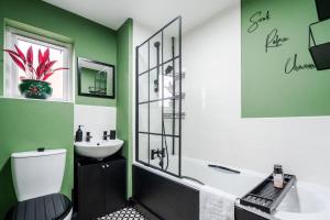 a bathroom with green walls and a sink and a toilet at 2 Bedroom Home with Garden and Free Parking in Litherland +49 photos