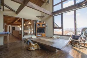 a living room with a wooden table and some windows at Sanso Harunoki staff-resident type - Vacation STAY 11615 in Furano