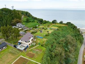 an aerial view of a house on a hill next to the ocean at Nihonkai Nou no yado Miharashitei - Vacation STAY 11631 in Itoigawa