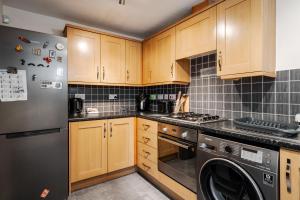 a kitchen with wooden cabinets and a black refrigerator at 2 Bedroom Home with Garden and Free Parking in Litherland