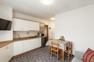 a kitchen with white cabinets and a table with a chair at Dolomitihouse BEDOL in Fiera di Primiero