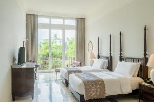 a hotel room with two beds and a balcony at Rumah Luwih Bali by IHG in Keramas