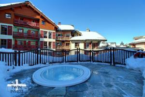 a hot tub in the snow in front of a house at ARC 1950, Appartement 2 chambres 6 personnes, Skis aux pieds, Sauna, Hammam, Jacuzzi, Piscine intérieure et extérieure in Arc 1950