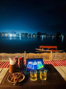 a table with a laptop and a plate of food and drinks at Dal lake group of houseboats in Srinagar