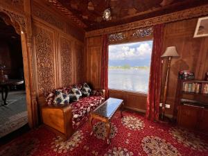 a living room with a couch and a large window at Dal lake group of houseboats in Srinagar