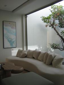 a white couch in a room with a large window at Pinepilla Poolvilla Huahin in Hua Hin