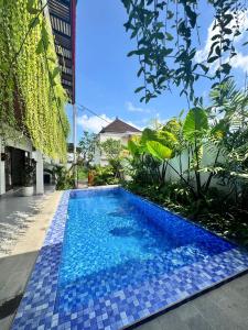 een zwembad met blauwe tegels voor een gebouw bij Casa Serena Cemagi in Canggu