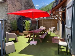 a patio with a picnic table and a red umbrella at KLodge-Chalet Pyrénées- Sauna-Aventures Montagne in Vignec